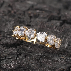 Macro shot of hip hop gold ring with heart-cut cubic zirconia stones on dark rock