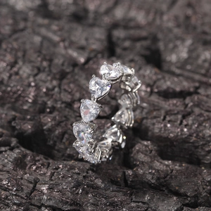 Macro shot of silver heart-cut eternity ring with sparkling zircon stones on dark stone
