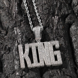 Détail macro du pendentif KING serti de zircons brillants et chaîne torsadée