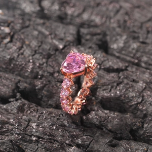 Détail macro d'une bague en zircon rose en forme de cœur plaqué or rose sur charbon