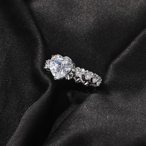 Détail d'une bague avec zircon en forme de cœur sur un tissu en soie noire élégant