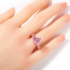 Gros plan d'une bague en zircon rose en forme de cœur en or rose sur une main