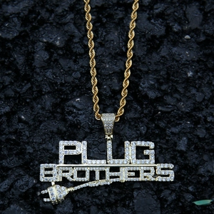Primer plano de cadena de oro y colgante PLUG BROTHERS con circonitas sobre fondo oscuro