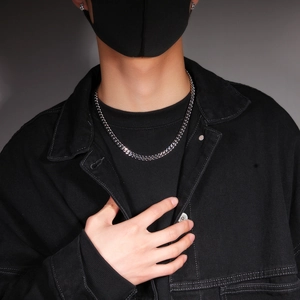 Close-up of a 12mm silver Cuban link chain necklace worn by a male model in streetwear