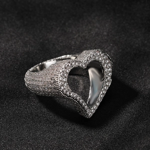 Détail macro d'une bague argentée au design cœur évidé sertie de zircons brillants
