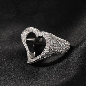 Gros plan sur bague cœur en argent sertie de zircons sur fond de soie noire élégante