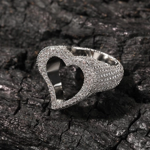 Gros plan sur une bague coeur évidé en argent avec zircons sur fond de charbon noir