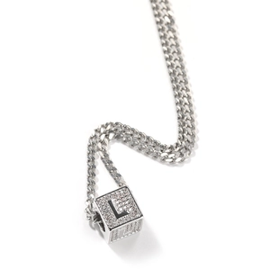 Détail macro du pendentif cube argenté avec pierres brillantes et lettre L noire