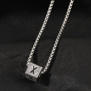 Gros plan détaillé d'un pendentif cube argenté avec lettre X en cristal sur chaîne box