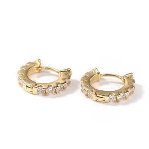 Close-up of gold plated huggie earrings with cubic zirconia pave setting on white background