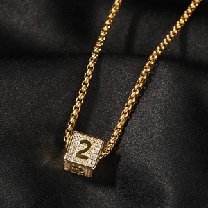 Vue macro du pendentif cube doré avec numéro 2 et zircons sur soie noire élégante