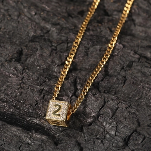 Gros plan d'une chaîne cubaine dorée avec pendentif cube numéro 2 sur charbon