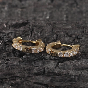 Macro shot of gold huggie earrings with cubic zirconia pavé set on a dark rock
