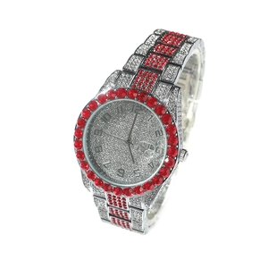 Détail d'une montre de luxe argentée avec strass rouges et blancs et grand cadran rond