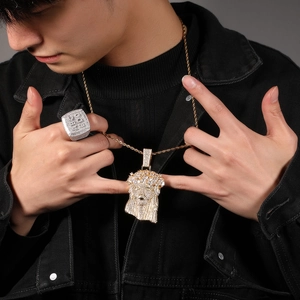 Close-up of hip hop Jesus pendant and square iced out ring on male model wearing denim