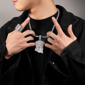 Macro detail of iced-out silver Jesus pendant and square ring with tennis chain