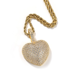 Detailopname van 3D gouden hartvormige hanger met zirkoon op een dikke touwketting