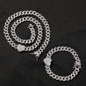 Detail view of silver iced-out cuban chain set with heart pendant on black background