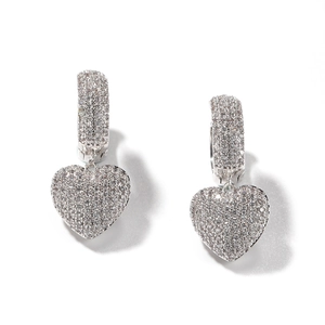 Close-up of hip-hop pavé heart earrings featuring white cubic zirconia on silver setting