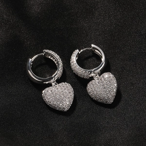 Close-up of silver huggie earrings with iced out heart drop and micro-pave zircons