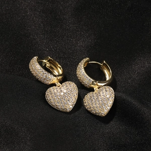 Macro shot of gold-plated hip hop heart earrings with full cubic zirconia stones on black silk