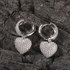 Macro shot of heart-shaped drop earrings with micro-pave zircons on a dark wood background