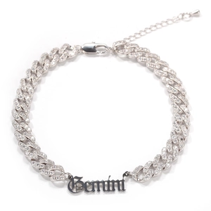 Macro detail of silver Cuban anklet with Gemini gothic plate and micro-pave crystals