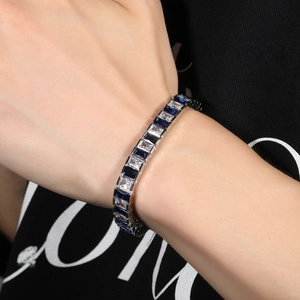 Détail d'un bracelet de tennis hip hop avec zircons bleus et transparents portés au poignet