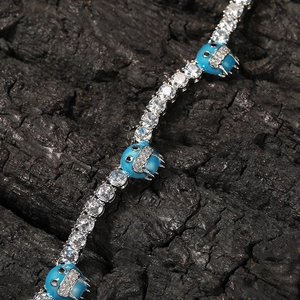 Detalle macro de la pulsera de tenis con diamantes y dijes de monstruos azules
