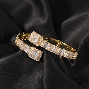 Makro-Detail des goldenen Hip-Hop-Armreifs mit funkelndem Zirkonia-Besatz auf schwarzer Seide