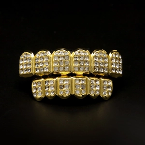 Detail shot of gold-plated hip hop teeth grills with iced out rhinestones on black background