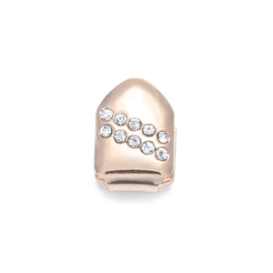 Macro detail of gold plated hip hop single tooth grill set with white rhinestones