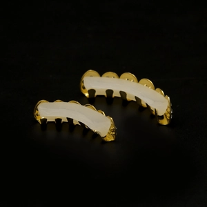 Detail view of hip hop gold teeth grills set with silicone fixing bars on black background