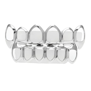 Détail d'un ensemble de grillz argentés avec crocs évidés sur support blanc