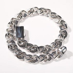 Detailed macro shot of silver Cuban link chain featuring geometric engraved patterns and box clasp