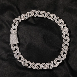 Detail of silver iced-out cuban link chain necklace with infinity links on black silk