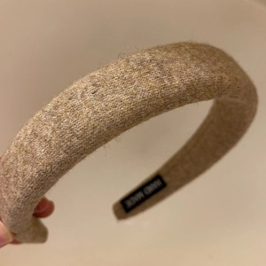 Detail of light beige knitted headband texture with a handmade black inner label