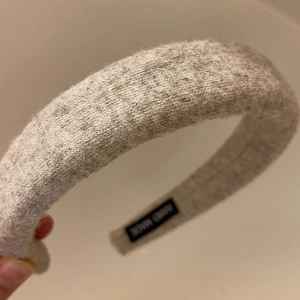 Close-up of handmade grey wool headband with texture detail and woven internal label