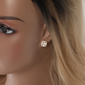 Detail of square gold earrings with channel-set baguette cubic zirconia and center stone