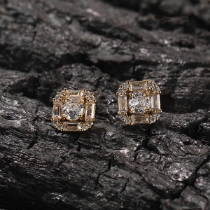 Macro shot of gold square halo stud earrings with sparkling round and baguette zircon stones