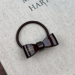 Detailed macro view of deep brown acetate bow hair tie with gold France Handmade lettering