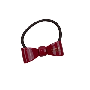 Red French style acetate bow hair tie with gold handmade lettering on white background