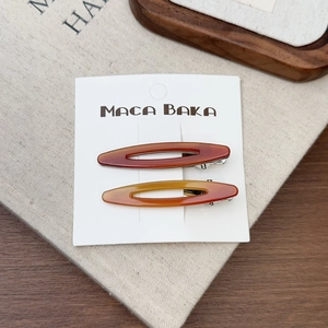 Gros plan de barrettes à cheveux en acétate ambré sur une carte blanche sur toile beige
