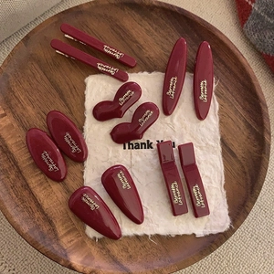 Vintage burgundy hair clips set with gold lettering in a wooden tray display