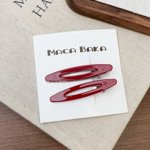 Gros plan d'une paire de barrettes à cheveux rouges ovales et ajourées sur carte