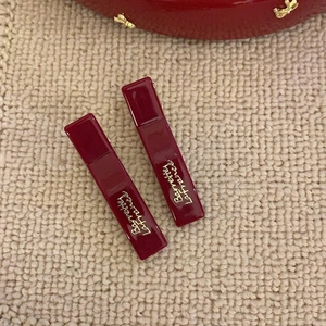 Close-up of two wine red French style rectangular hair clips with gold Barrette lettering