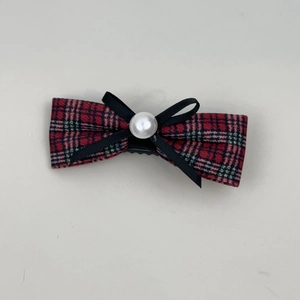 Detail of red and green plaid hair bow with black ribbon, pearl accent and metal clip