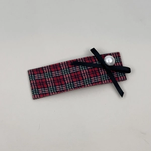Detail of red and green plaid hair clip with black ribbon bow and elegant pearl accent
