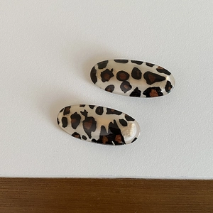 Top view of a pair of leopard print oval hair clips in polished translucent resin