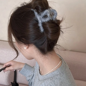 Dettaglio della molletta per capelli grigia in peluche con texture soffice effetto mohair